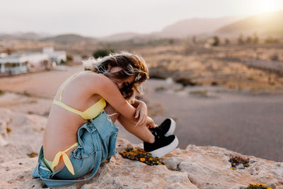 Woman sitting on rock at beach