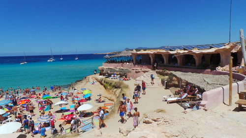 People at beach against clear blue sky