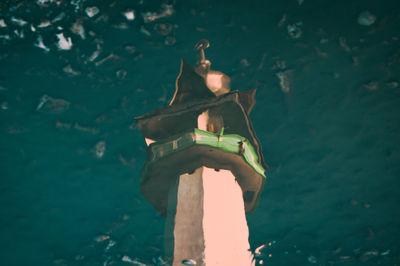 Close-up of illuminated lamp post in sea against building