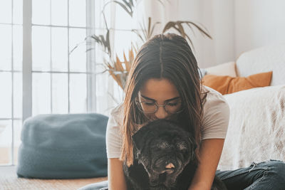 Woman kissing dog at home