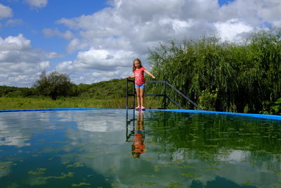 Woman standing by lake against sky