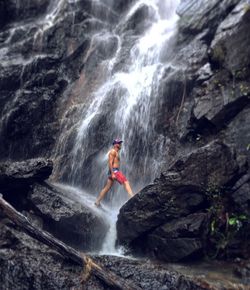 Man surfing on rock in waterfall