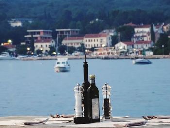 Bottles and containers on table against river during sunny day