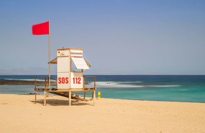 Information sign on beach against clear sky