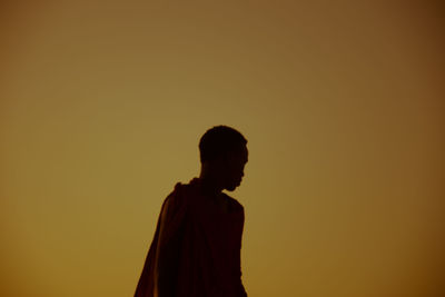 Man standing against orange sky during sunset