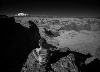 Rear view of woman standing on rock against sky