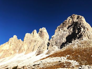 Low angle view of snowcapped mountains against clear blue sky