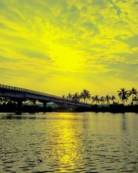 Bridge over river against orange sky