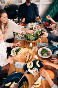 High angle view of happy friends enjoying food in cottage