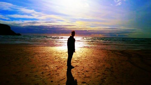 Silhouette man standing on beach against sky during sunset