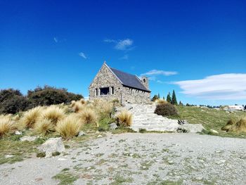 Old building on landscape against blue sky