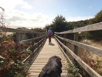 Rear view of woman walking on footbridge