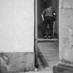 Rear view of senior man walking against wall