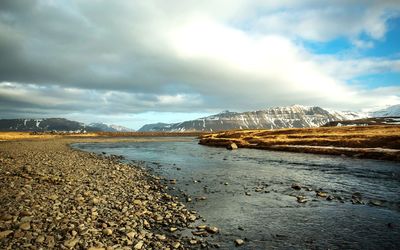 Scenic view of sea by mountains against sky