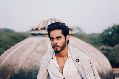 Portrait of young man standing against sky