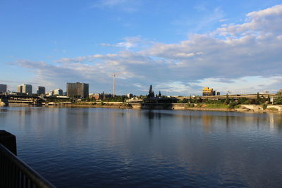 View of buildings by river against sky