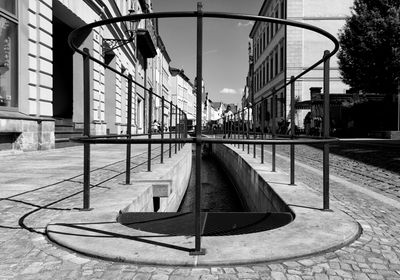 Street light on footpath by building against sky