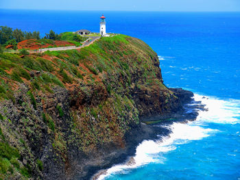 Lighthouse on beach by sea against sky