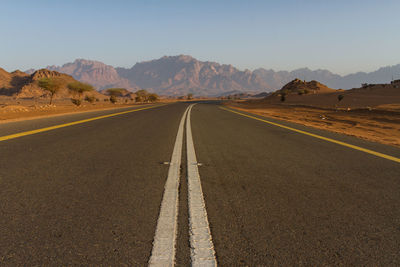 Road leading towards mountains against sky