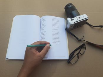 High angle view of hand holding book on table