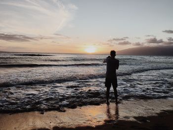 Silhouette man on beach against sky during sunset