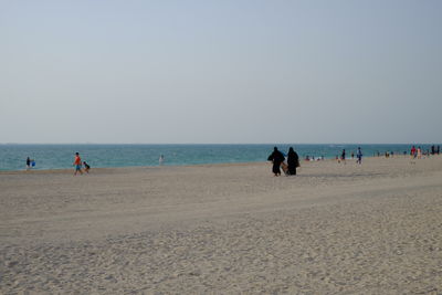 People on beach against clear sky