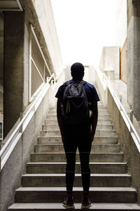 Young man with backpack standing in front of staircase