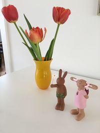 Figurines by flower vase on table