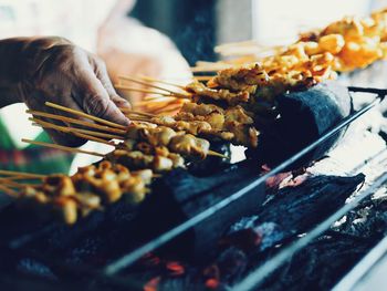 Close-up of man preparing food on barbecue grill