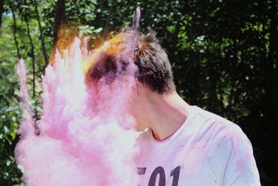 Young man in smoke against trees 