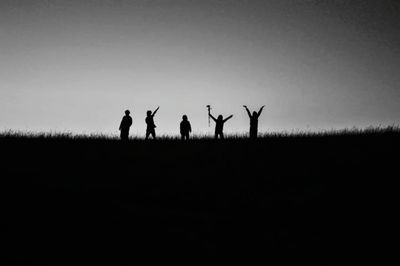 Silhouette people standing on field against sky