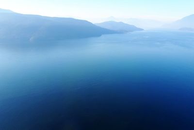 Scenic view of sea and mountains against blue sky