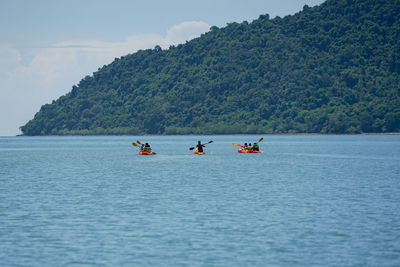 People in boat on sea against mountains