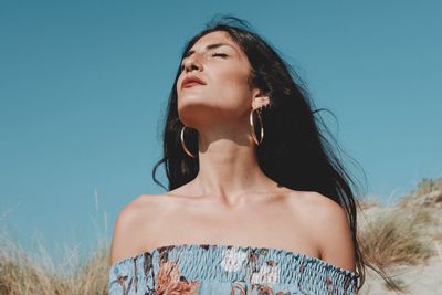 Young woman looking away against clear sky