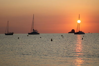 Silhouette sailboats in sea against sky during sunset