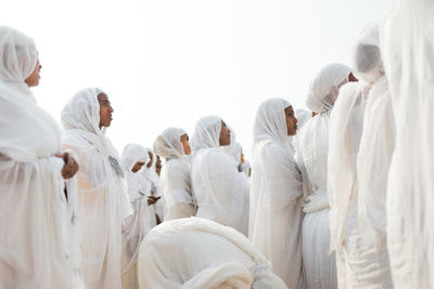 People praying in city against sky