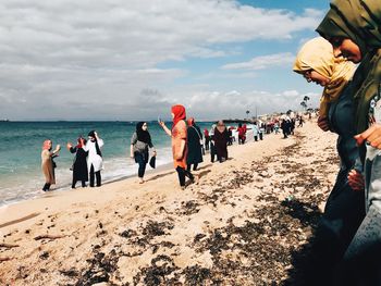 People at beach against sky