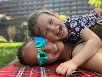 Portrait of smiling mother with cute daughter lying outdoors