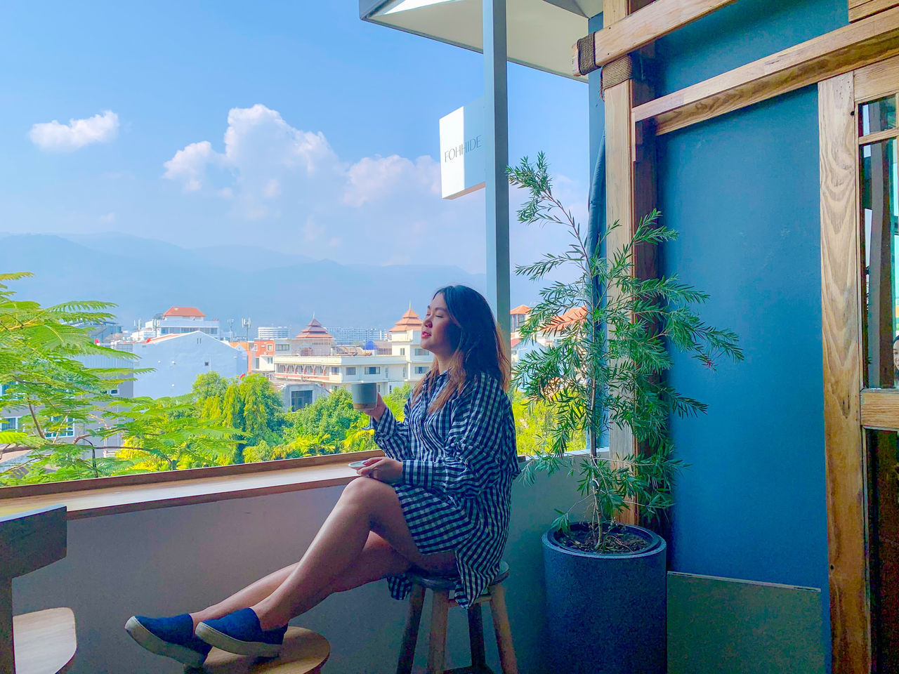 WOMAN SITTING ON CHAIR AGAINST BLUE SKY