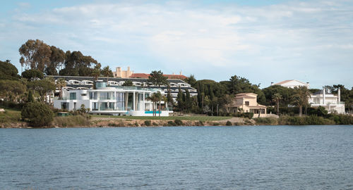 Buildings by river against sky