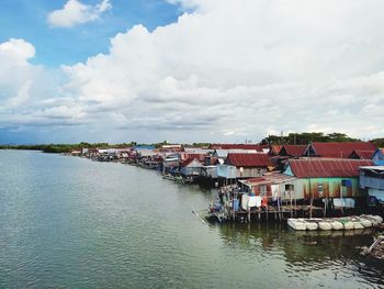 Houses by river and buildings against sky