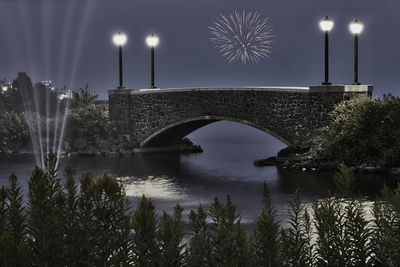 Arch bridge over river against sky at night