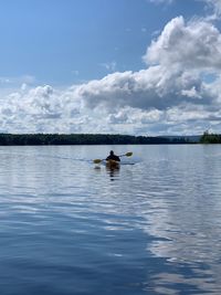 Man kayaking in lake against sky