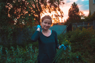 Portrait of woman holding plants standing outdoors