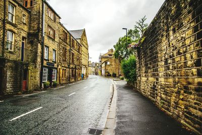 Road amidst buildings in city against sky