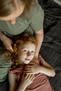 Daughter lying on mother's lap at home