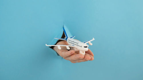 Caucasian woman holding a miniature of an airplane on a blue background.