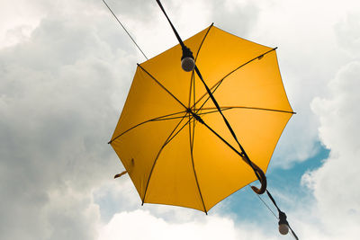 Low angle view of yellow umbrella against sky