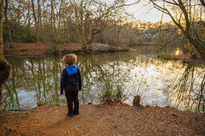 Boy watching flock of birds during sunset in the forest at the lake
