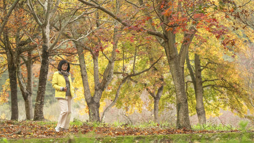 Woman standing under the trees in the autumn season